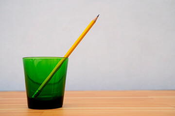Yellow wooden pencil in green glass isolated on white background Work-from-home banner idea WFH with copy space for text that runs or wraps around.