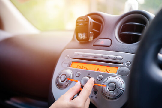 Women Turning Button On Car Radio For Listening To Music