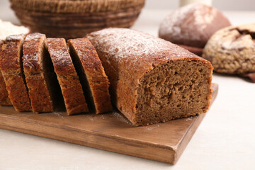 Cut freshly baked bread on white wooden table, closeup