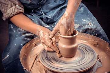 Potter's hands and potter's wheel. Close-up.