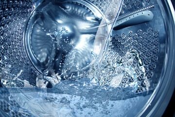Closeup view on washing machine drum filling with water