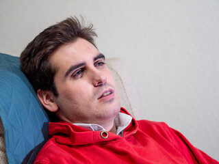 Hombre joven con ojos azules cansado en el sofá