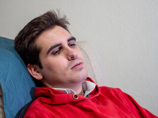 Hombre joven con ojos azules cansado en el sofá