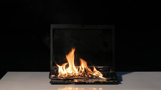 Laptop burning in flmes on a desk, fire hazard