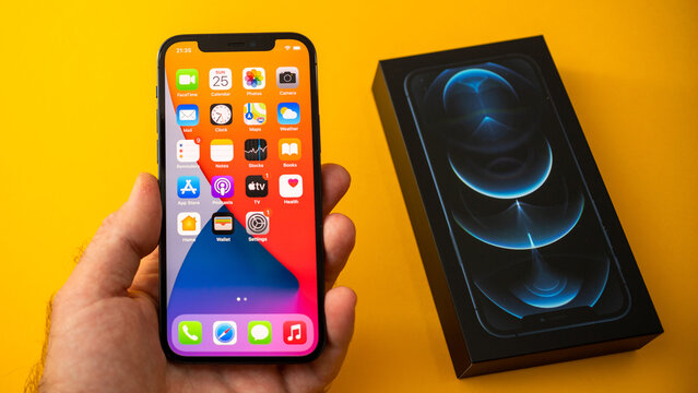 Paris, France - Oct 23, 2020: POV man holding new iPhone 12 Pro Max 5G smartphone model by Apple Computers close-up of Pacific Blue mobile phone device - all homescreen apps