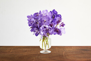 Bouquet of purple orchids in glass vase on wooden table © udom