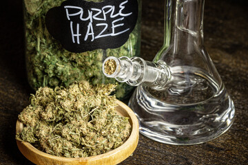Jar and wooden bowl of weed with glass water pipe
