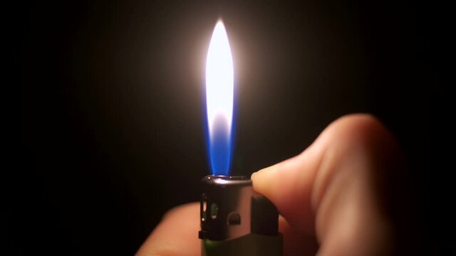 The lighter is held in the hand and lit. The lighter produces a spark