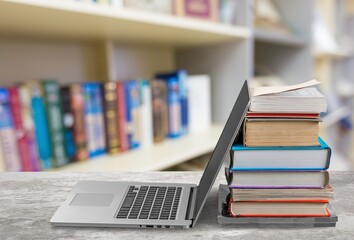 Stack of books with modern laptop on table
