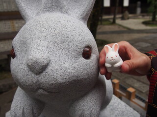 A cute little white rabbit statue and a large stone statue at Okazaki Shrine, Kyoto, Japan