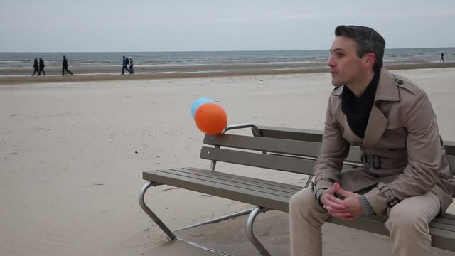 Cinema graphic. Young man is  sitting on a bench on a beach. Two balloons.