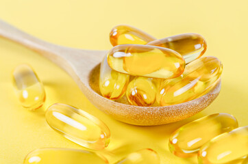 Fish oil capsules in wooden spoon.