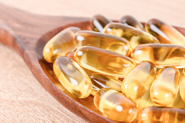 Fish oil capsules in wooden spoon.