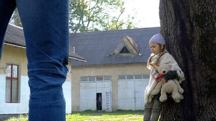 Mistreated child. Little girl with teddy bear is scared. Child in danger.