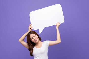 Smiling beautiful Asian woman holding empty speech bubble isolated on purple studio background