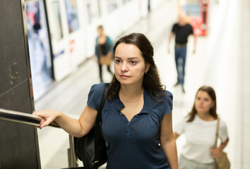 Focused young brunette coming out of metro station, walking up stairs ..