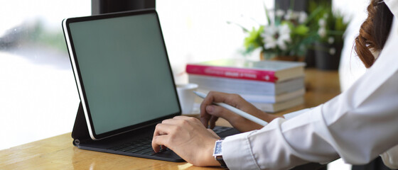 Female hands working with mock up digital tablet on wooden table