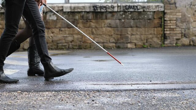 blindness, handicap - young blind man walks helped by his friend