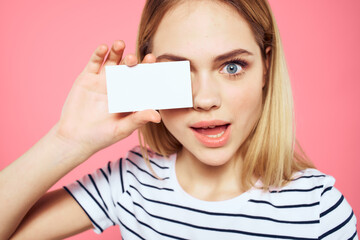 woman striped t-shirt business card in hands emotions pink background copy space