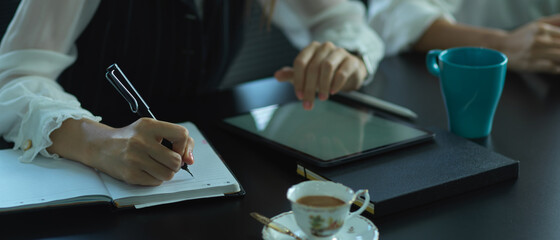 Female worker taking note while working with digital tablet in meeting room