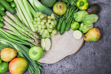 vegetables and fruits.
Green fruits and vegetables with a wooden board are arranged in a semicircle on the left with space for text on the right, a close-up top view.