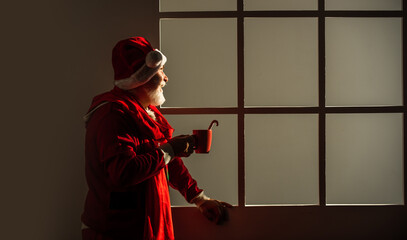 funny senior man in santa claus costume. happy new 2021 year. merry christmas. bearded santa in hat drink milk or cocoa. xmas presents and gift shopping time. winter holiday joy