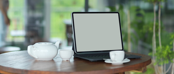Workspace with mock up blank screen tablet with keyboard with pottery teapot set