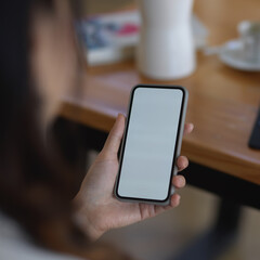 Female hand holding smartphone include clipping path while sitting at workplace