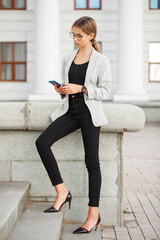 Portrait of a young beautiful girl in a gray jacket and black jeans