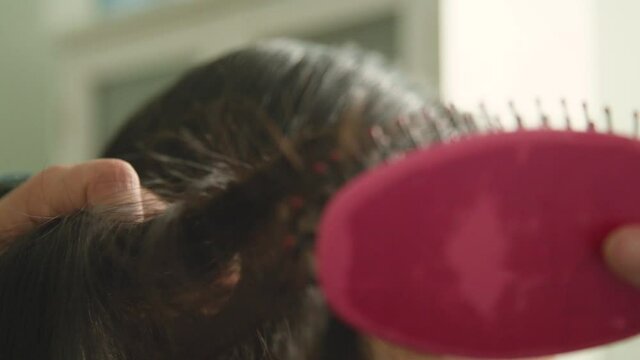 Extreme close up young woman detangle her hair with brush, slow motion