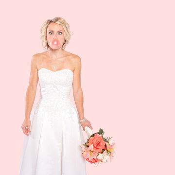 A beautiful blonde young bride isolated on pink background.
