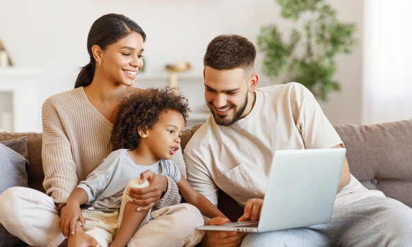 Diverse family using laptop on sofa together.