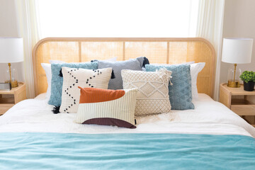close up of new bed comfort with decorative pillows ,headboard and side table lamp.