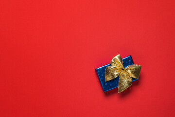Blue gift box with a gold bow on a red background.