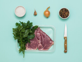 A bunch of parsley, vacuum-wrapped beef and spices on a wooden background.