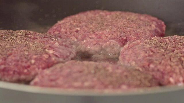 Red minced beef meat getting fried. Sizzling fat and evaporating water. Organic meat cooking for a healthy meal.  Grass fed beef. Boody meat patties.