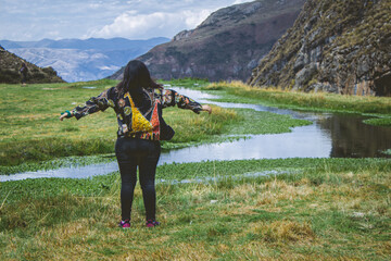 Turista disfrutando el aire de laguna en Ayacucho mirando el horizonte en frente y un río a su lado