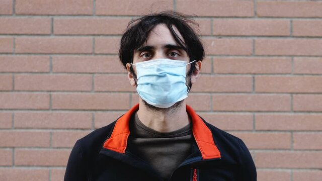 covid 19 - young serius man takes off his msk and smiling at camera