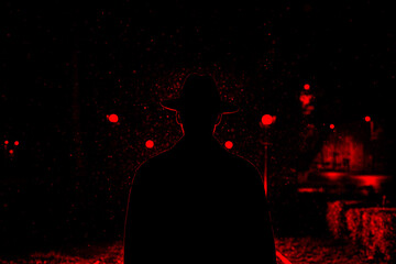 dark silhouette of a man in a hat in the rain on a night street