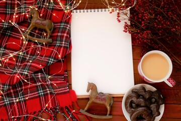 Christmas to-do list.Christmas and New Year Mockup.  notebook, mug with coffee, chocolate  cookies, decorative Christmas decorations, checkered scarfon a red wooden background.Winter holiday list