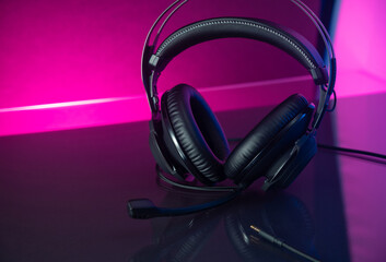 Fototapeta na wymiar Gamer Headphones Dark Background and colorful pink Light.