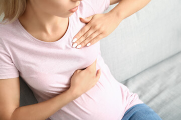 Young pregnant woman touching her breast at home