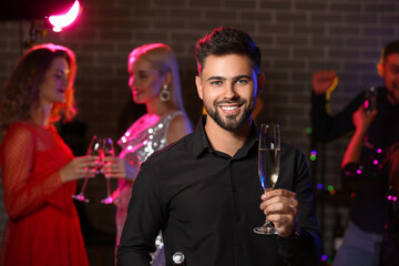 Young man with glass of tasty champagne at party in nightclub