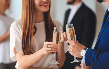 Young people drinking tasty champagne at party in office