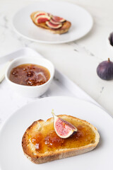 Plate with tasty sandwich with fig jam on table