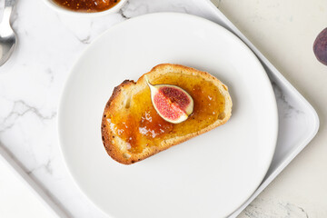 Plate with tasty sandwich with fig jam on table