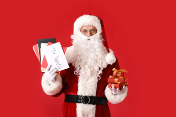 Santa Claus with letters and gifts on color background