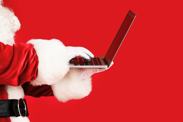 Santa Claus with laptop on color background