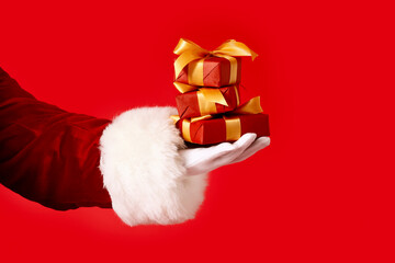 Hand of Santa Claus with gifts on color background