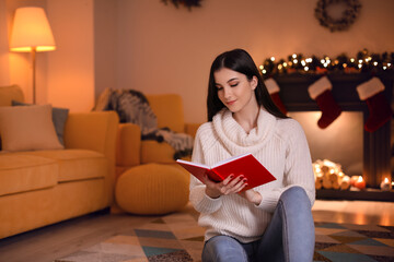 Obraz premium Beautiful young woman reading book at home on Christmas eve
